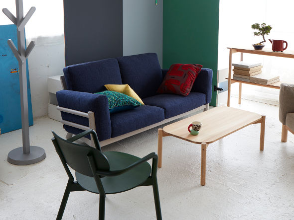 Sillón bajo Castor verde frente a un sofá azul, con perchero y mesa baja | Antifer