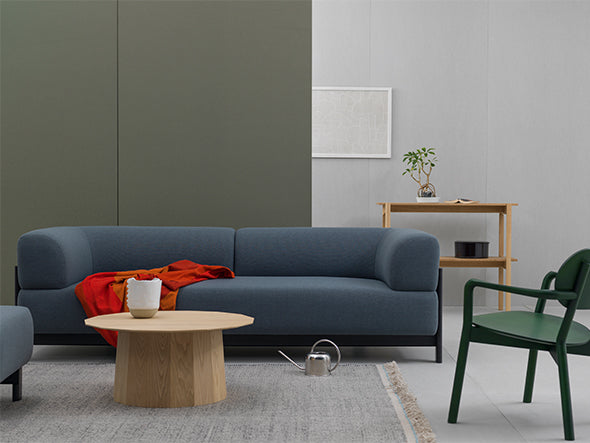 Sillón bajo Castor verde en un salón con sofá gris azulado, con mesa baja redonda | Antifer