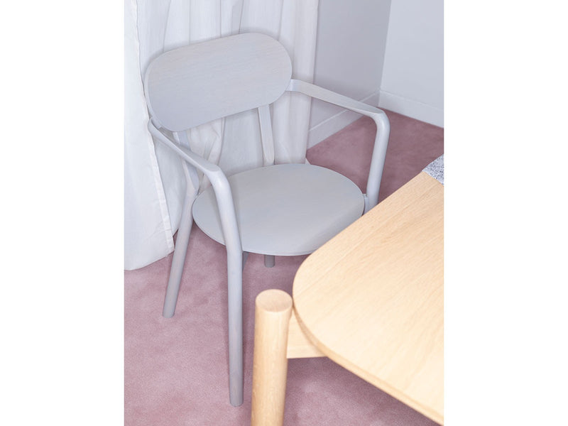 Butaca Castor Armchair Plus en acabado Grain Gray junto a una mesa de roble, primer plano