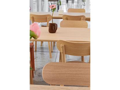 Stühle Castor aus Eiche, enger Bildausschnitt auf einen Showroom-Tisch mit Blumen | Antifer