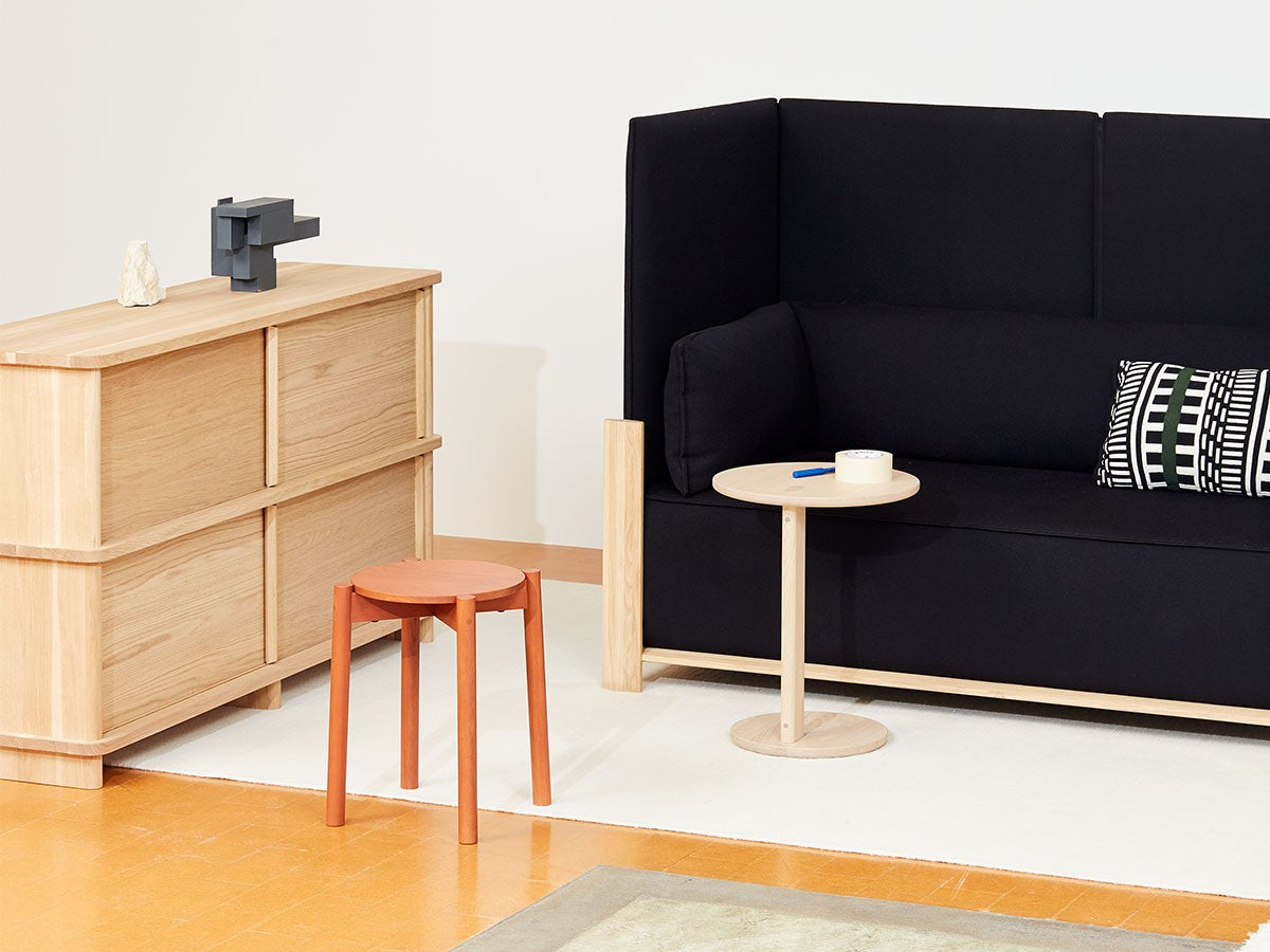Hocker Castor Plus in Terrakotta vor einem Sideboard Prop, gegenüber einem schwarzen Sofa Fence | Antifer