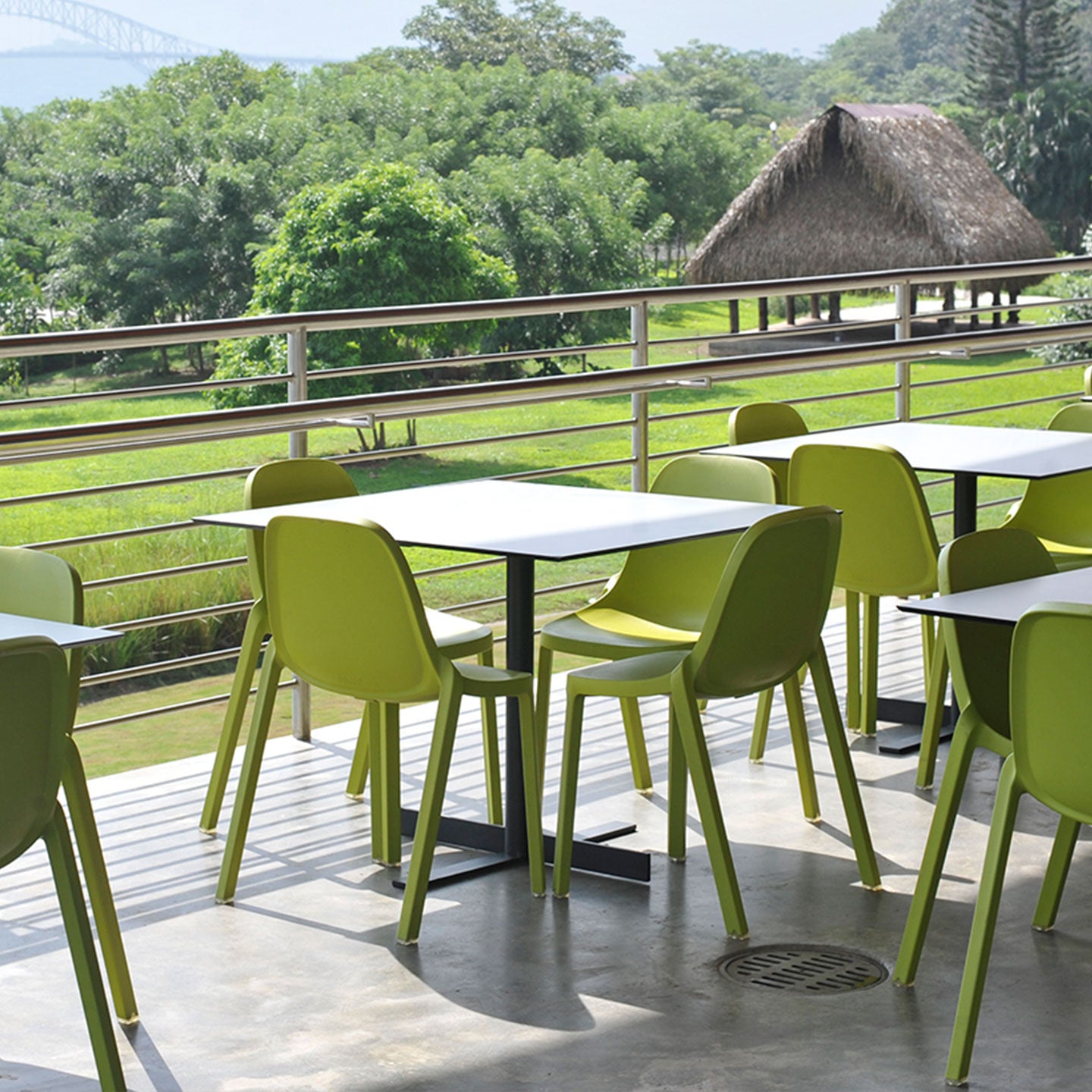 Café en extérieur à côté de la nature. Tables avec multiples chaises Broom Emeco vertes