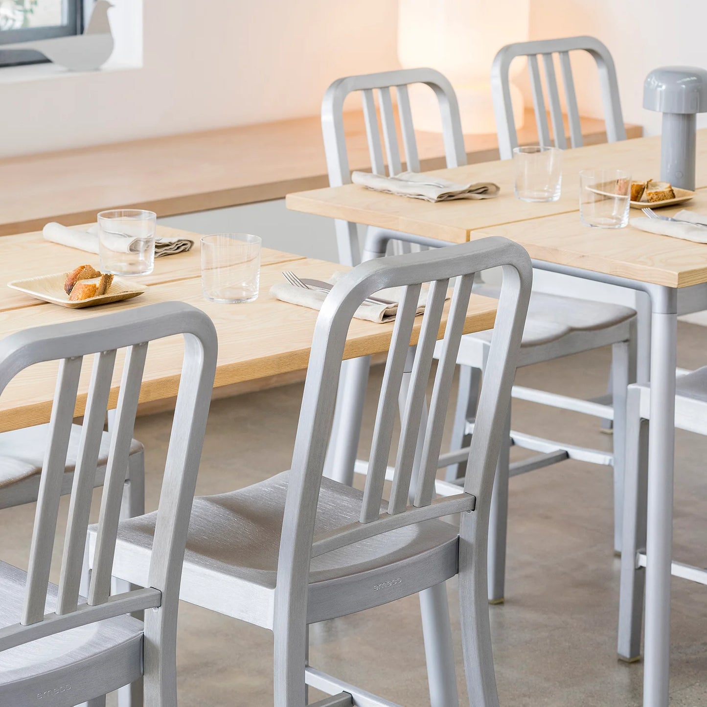 Gros plan sur Chaise Navy 1006 Emeco . 4 chaises autour d'une grande table à manger