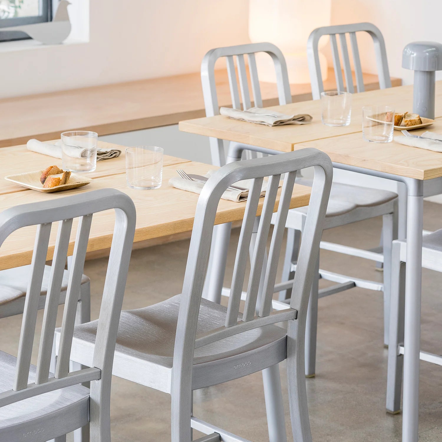 Gros plan sur Chaise Navy 1006 Emeco . 4 chaises autour d'une grande table à manger