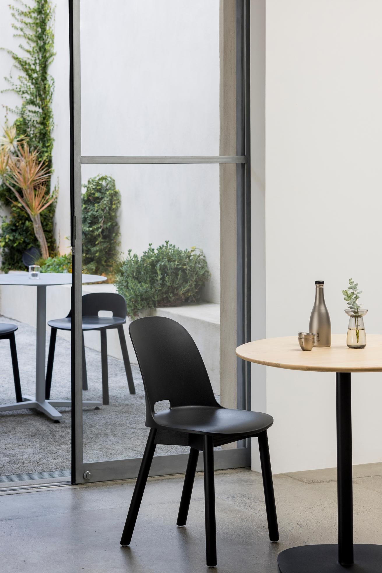 Scène de bar avec vue sur terrasse. Chaise Alfi Emeco design Jasper Morrison à dossier haut couleur gris foncé