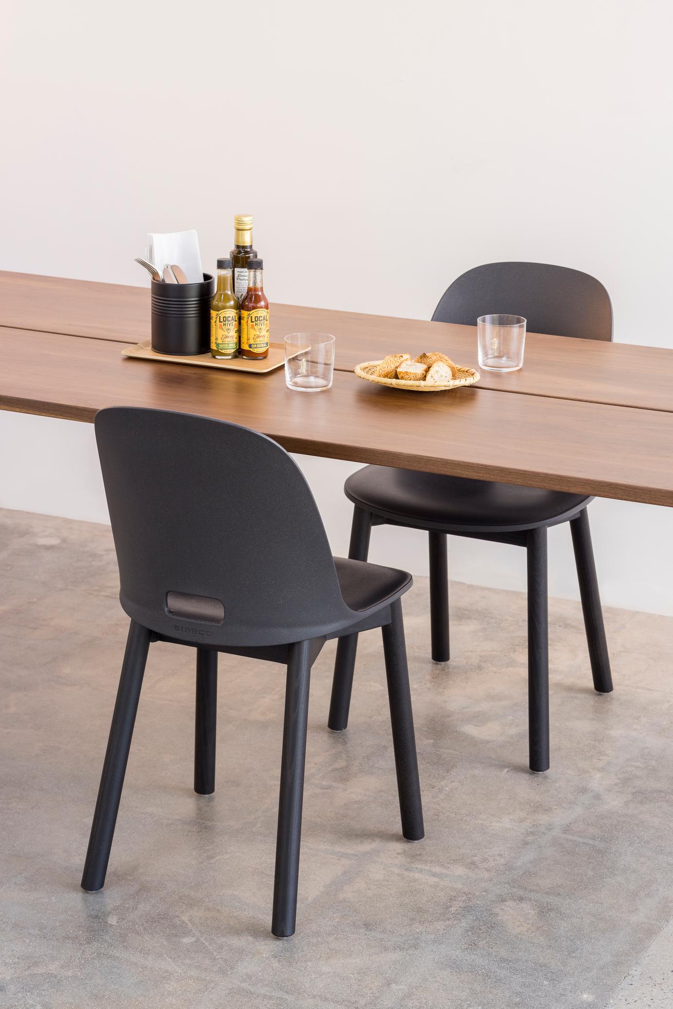 Gros plan sur table en noyer avec 2 chaises Alfi Emeco design Jasper Morrison à dossier haut couleur gris foncé