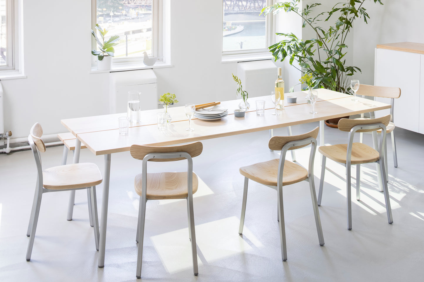 Salle à manger avec verres & chaises Emeco autour d'une table run en frêne.