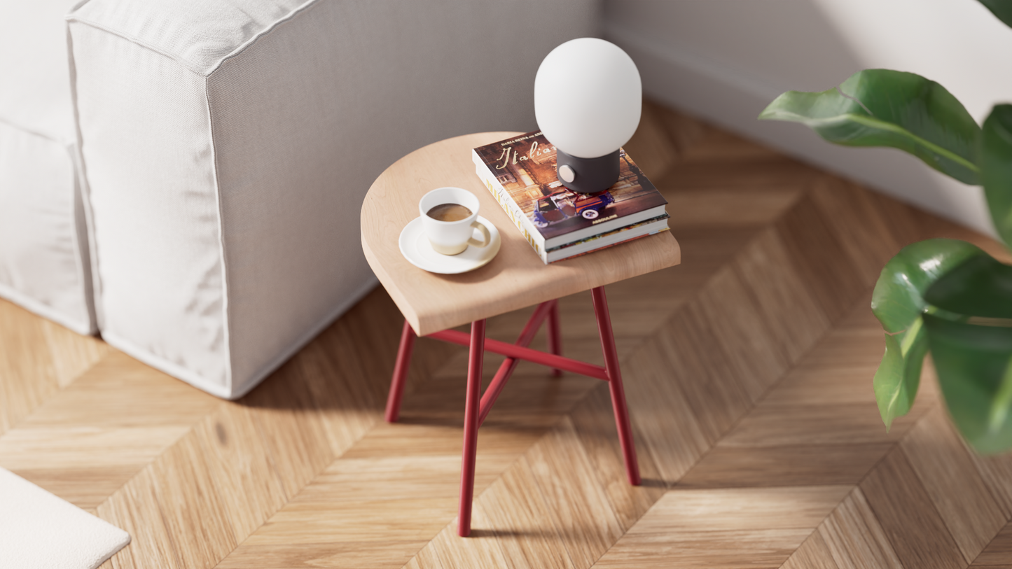 Tabouret bas Camarade en hêtre massif et acier couleur rouille aux côtés d'un canapé vue de haut