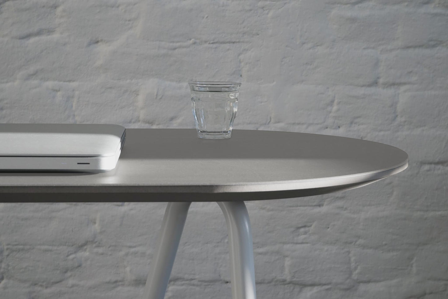 Gros plan sur petit bureau console minimaliste avec tréteaux Sinus avec verre d'eau et ordinateur