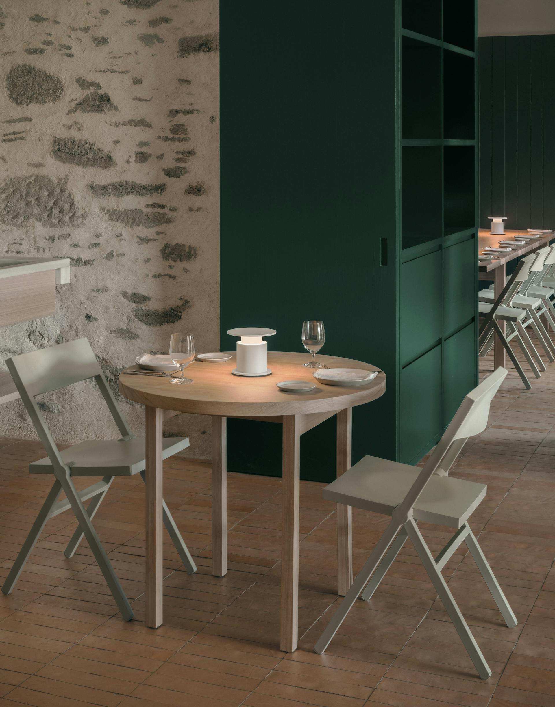 Lampe nomade blanche w241 Faro posée sur une table de restaurant tamisée. Wästberg.