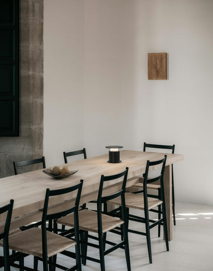 Lampe nomade w241 Faro noire posée sur une grande table communale avec 8 chaises. Wästberg. Design David Chipperfield