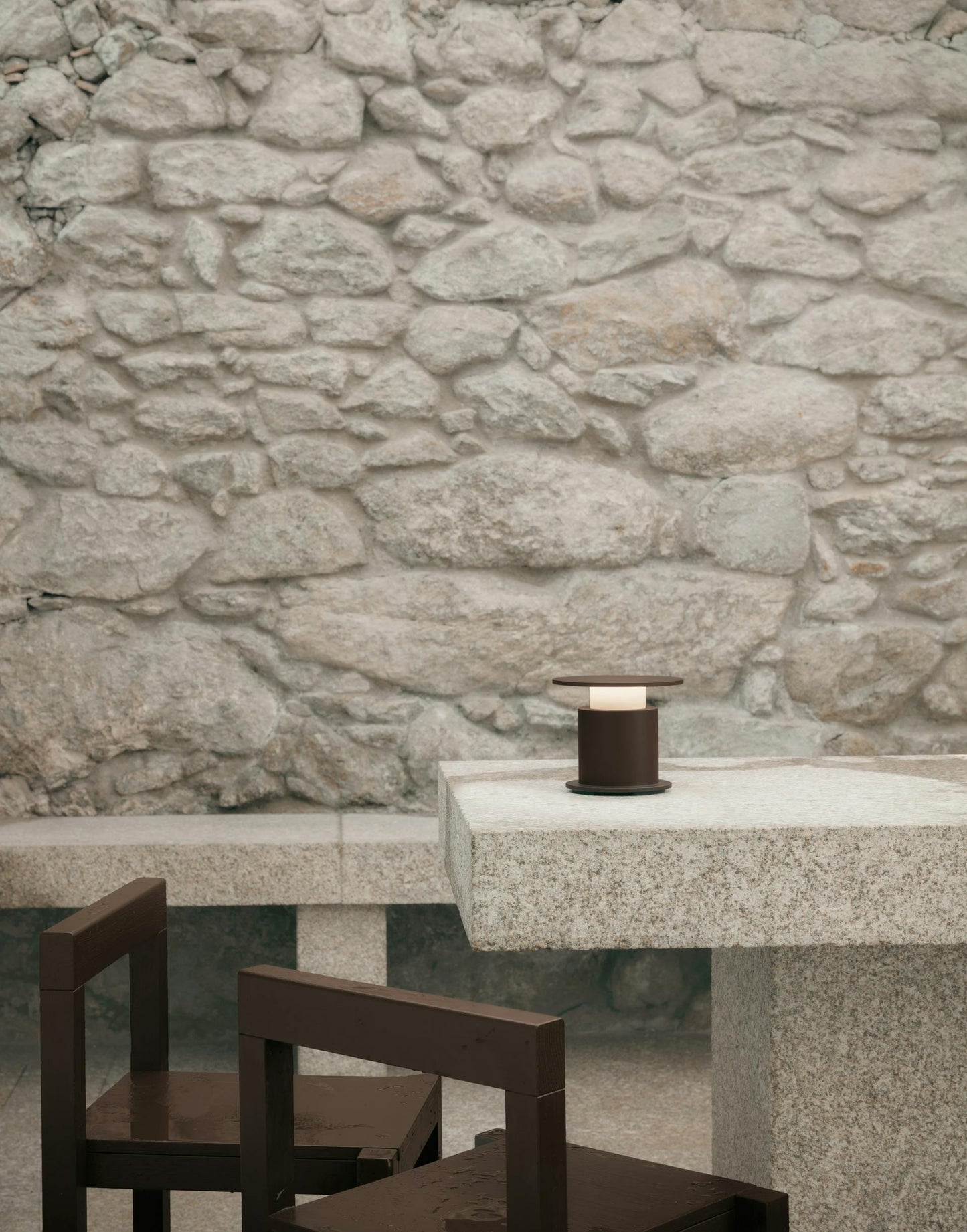 Lampe nomade w241 Faro chocolat posée sur une table en granit. Wästberg. Design David Chipperfield