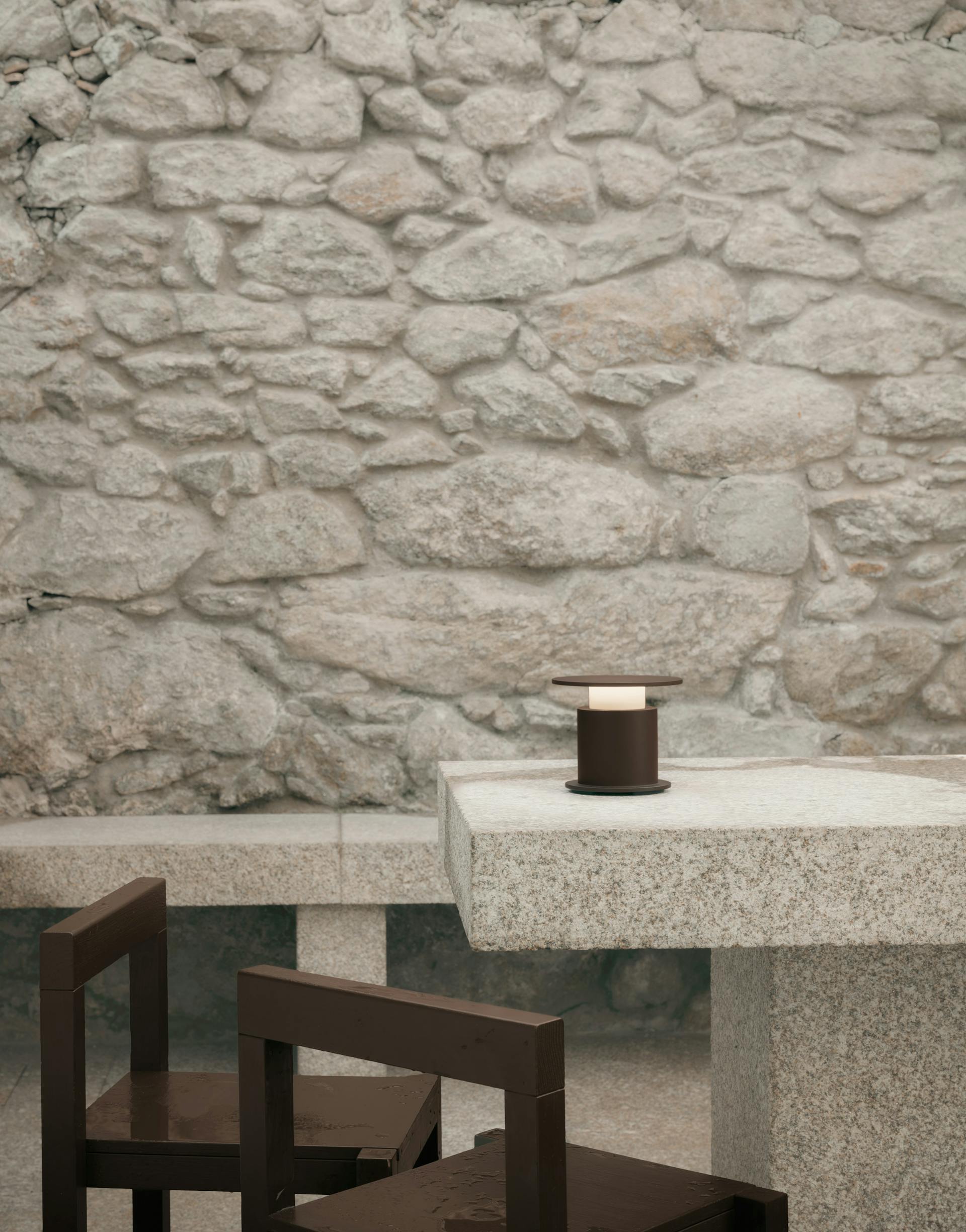Lampe nomade w241 Faro chocolat posée sur une table en granit. Wästberg. Design David Chipperfield