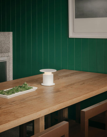 Lampe nomade w241 Faro rouge posée sur un table en chêne. Wästberg. Design David Chipperfield